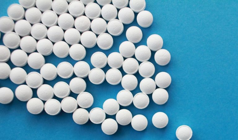 a pile of white pills sitting on top of a blue table